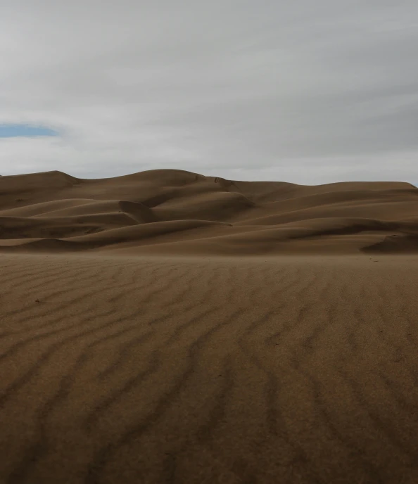 there are sand dunes in the desert, with a single person walking by