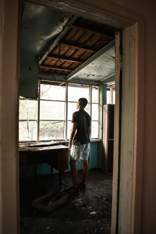the boy looks out from inside an abandoned building