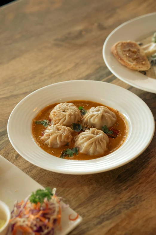 an asian food dish sits on a plate next to a bowl of soup