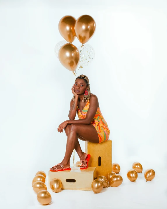 a beautiful woman sitting on a box in a yellow bathing suit with balloons