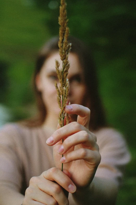 the girl is holding a plant in her hand