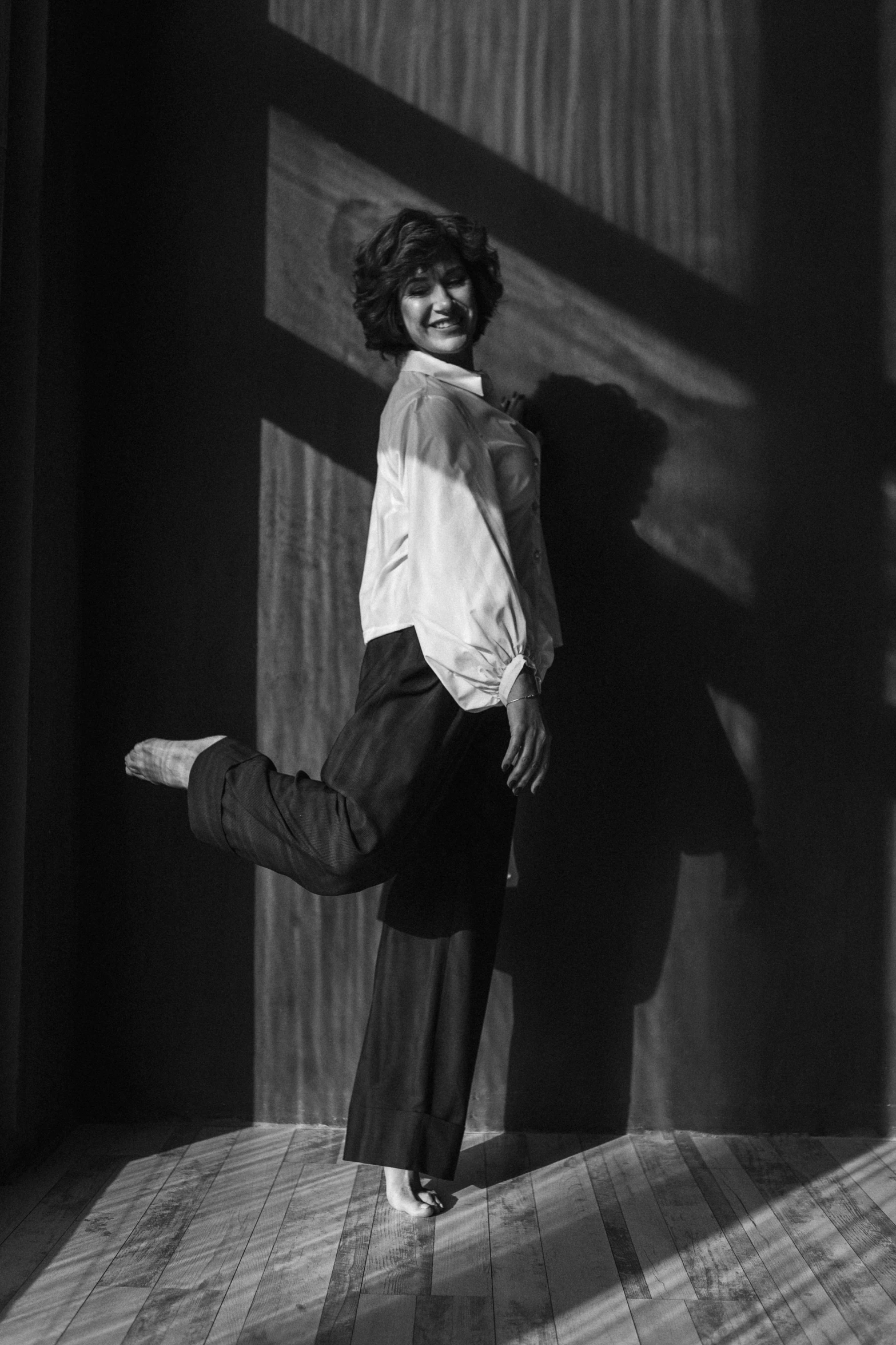 a woman in long pants and heels poses for a black and white po