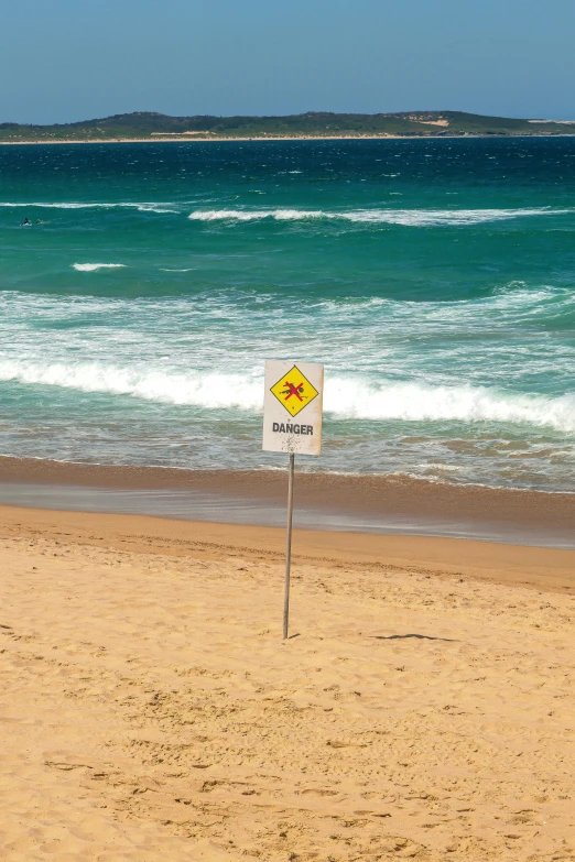 an image of a yellow and white caution sign on a beach