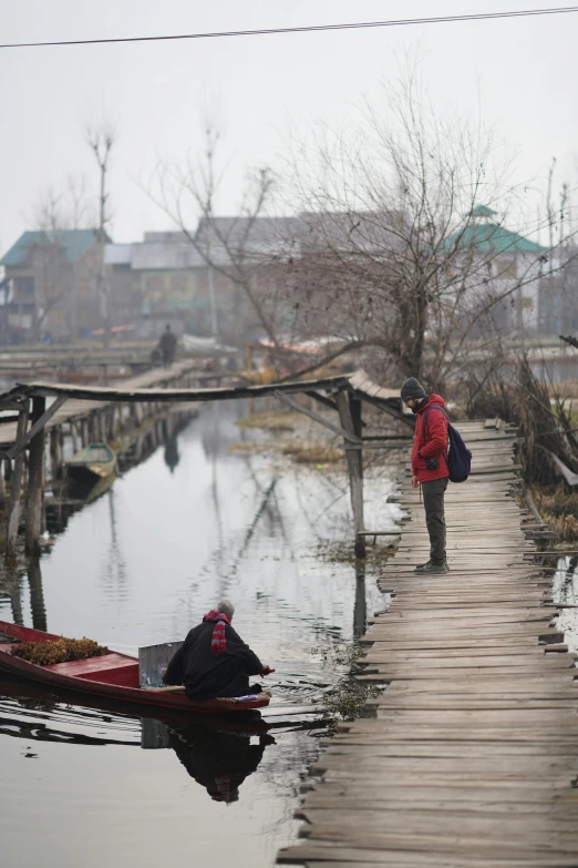 two people are standing on the dock on the river