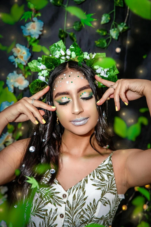 a young woman wearing makeup standing near green leaves