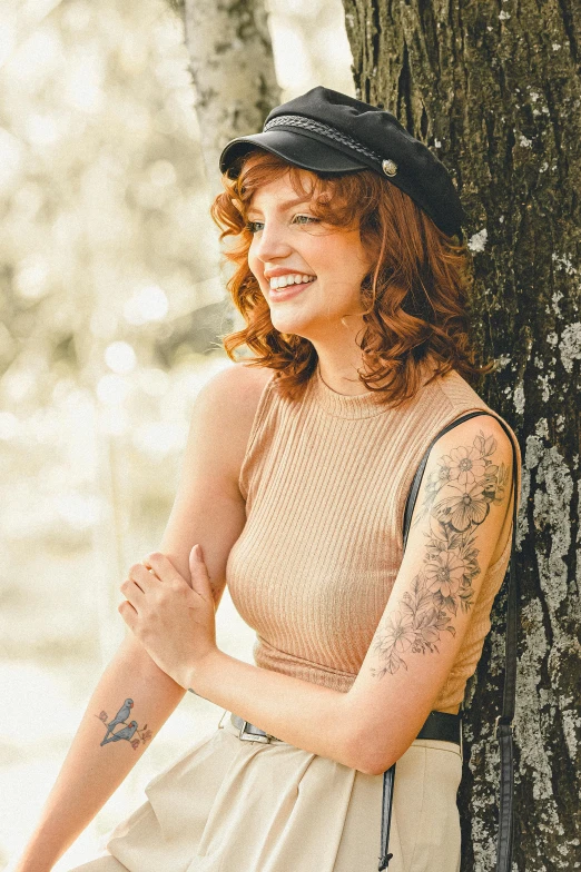 woman leaning against a tree while wearing a hat