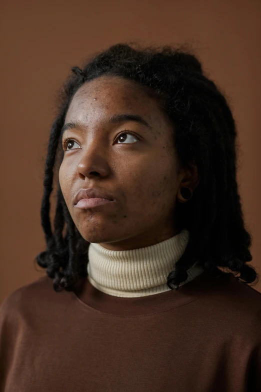a woman wearing a turtle neck sweater with dreadlocks