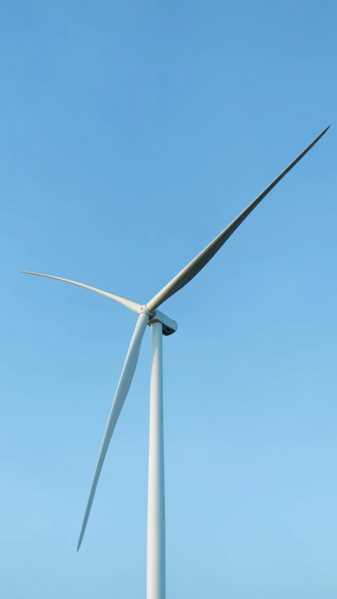 a wind turbine stands high in the blue sky