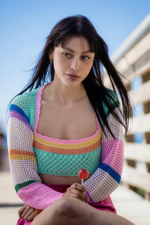 a woman sitting on a pier with a cigarette in her hand