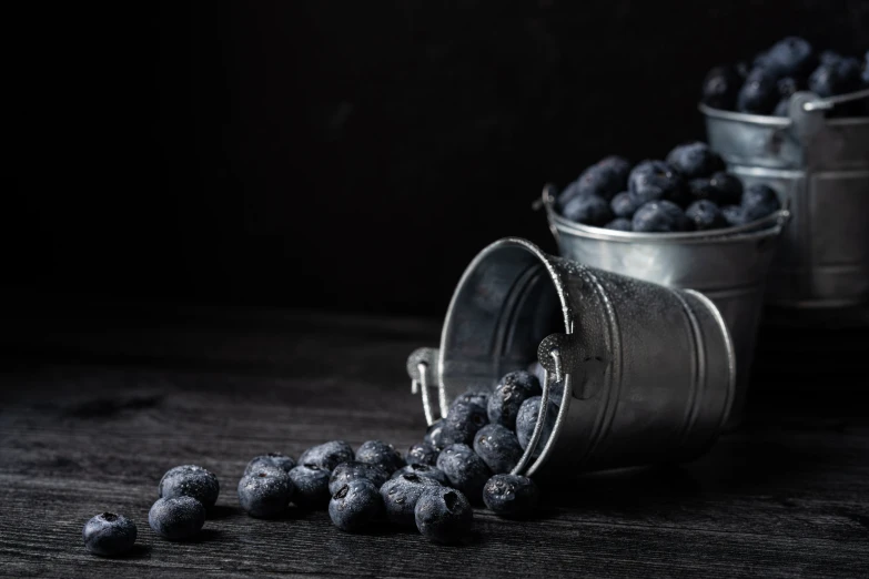 a group of buckets filled with blueberries on top of a wooden table