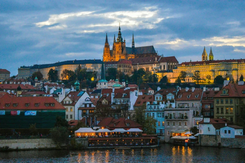 old european houses along the water with a castle on the hill