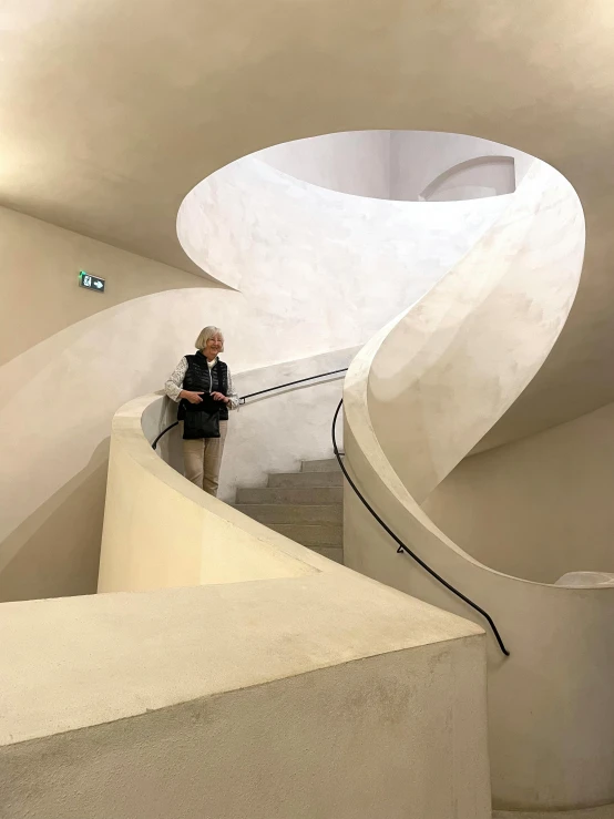 the man stands near the staircase of an artisticly designed building