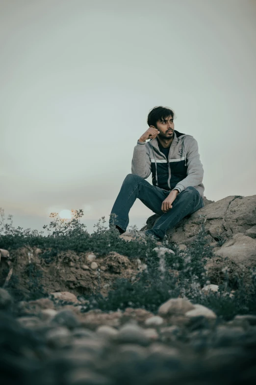 a man sitting on the ground next to rocks