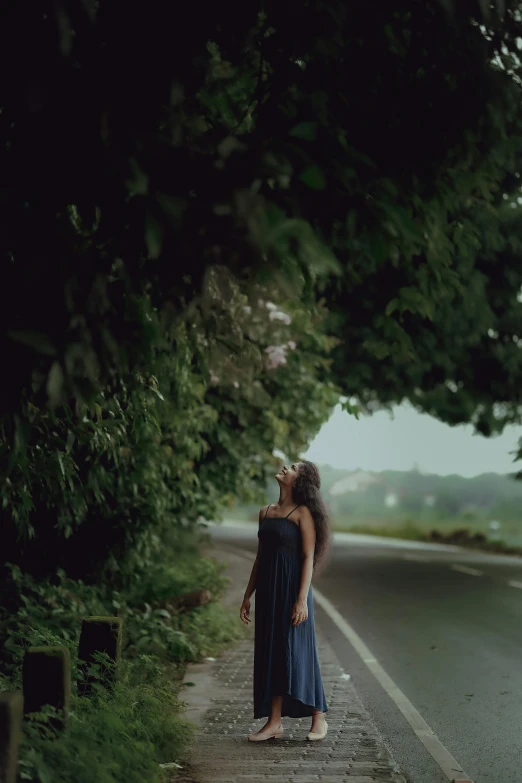 the woman is posing in front of a very long tree