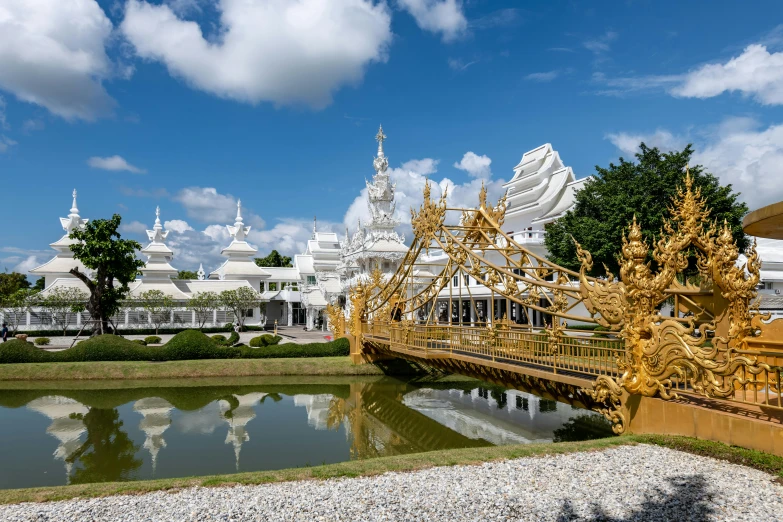 a small bridge spans across a pond in front of ornate buildings