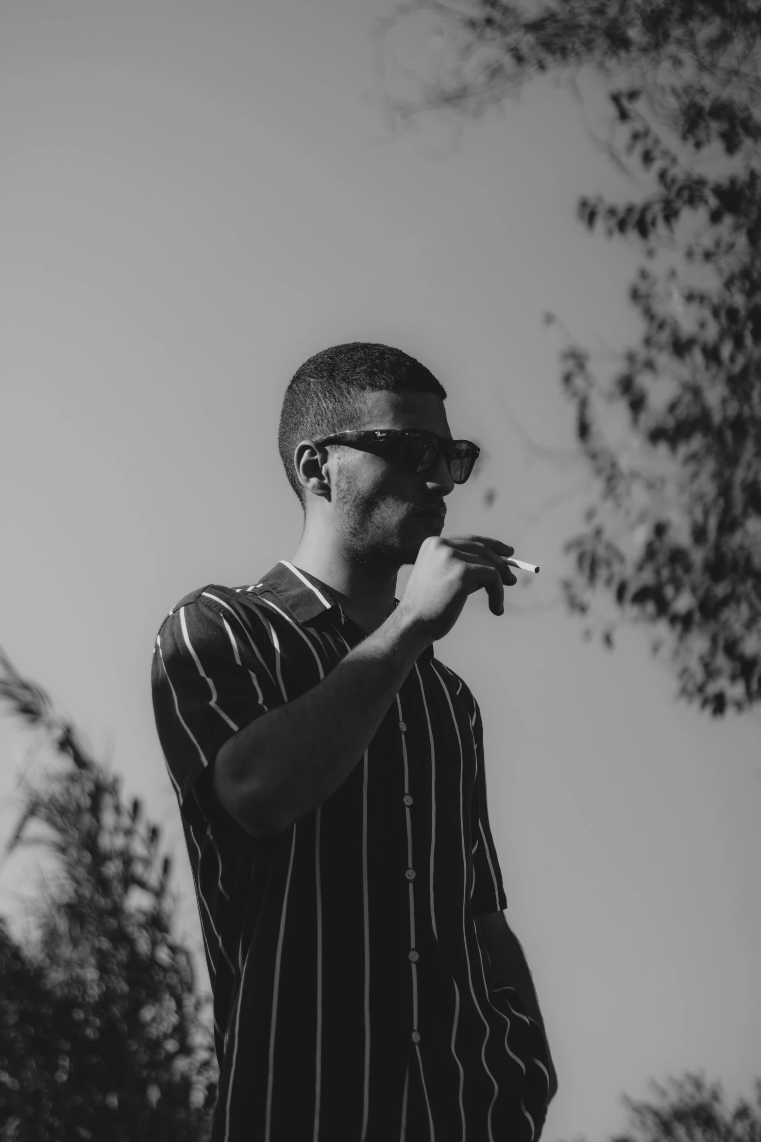 a man in striped shirt smoking cigarette outside