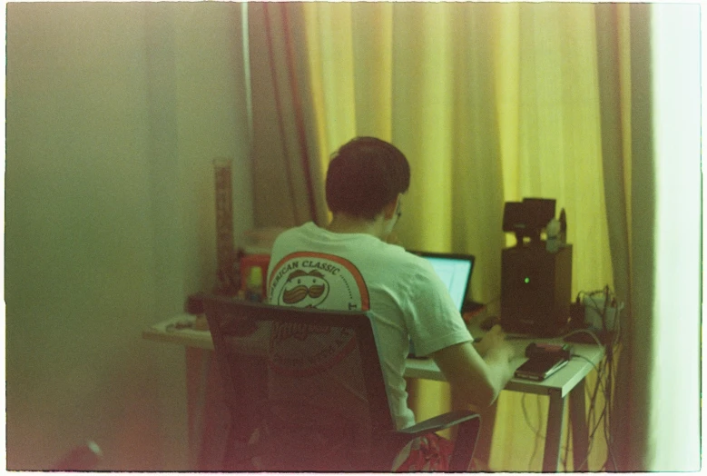 a boy at a desk in front of a laptop