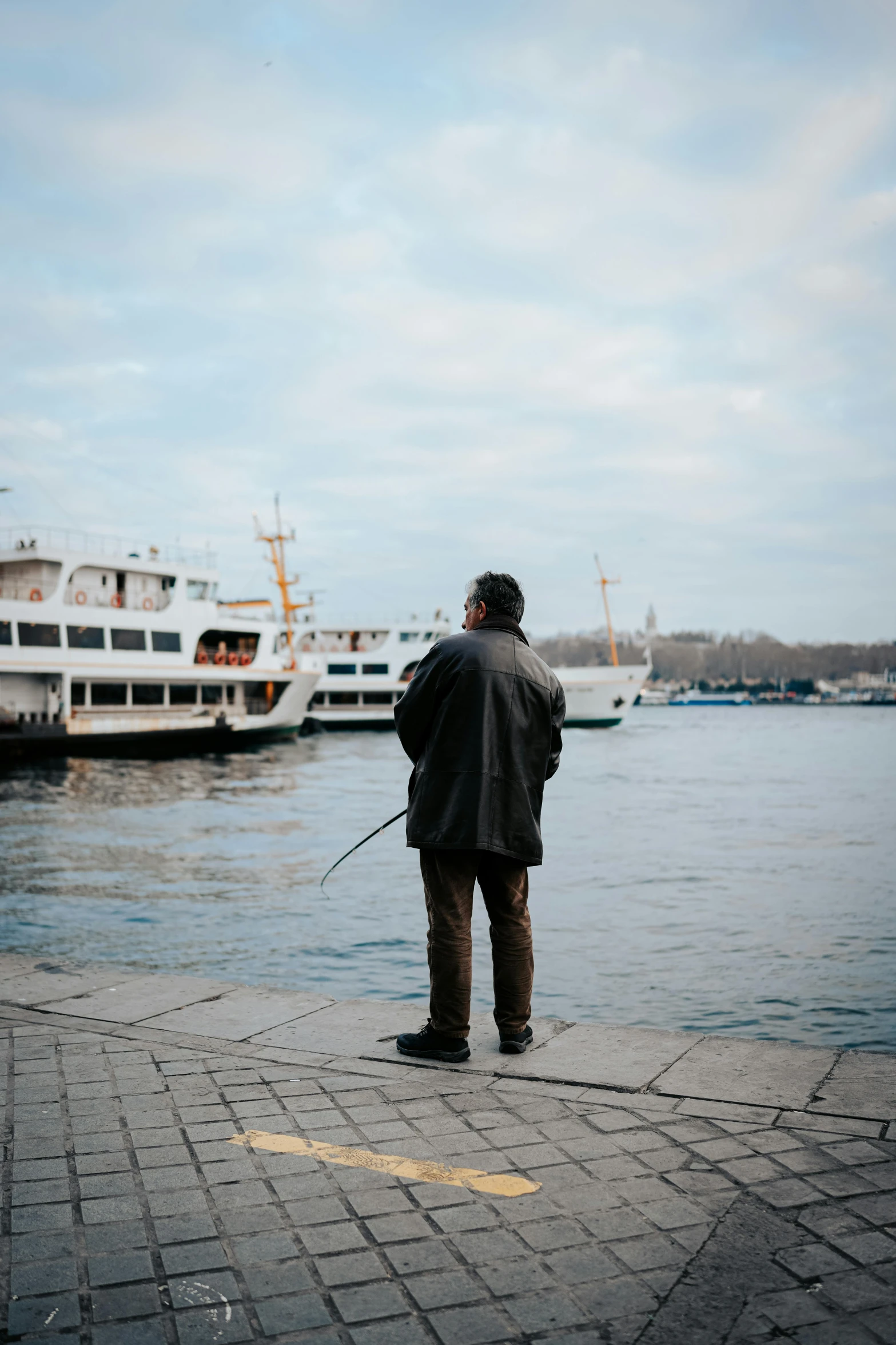 a man standing by the water with his back to the camera