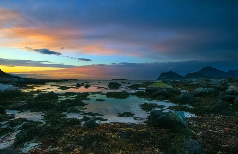 water sits under cloudy skies near a rocky beach