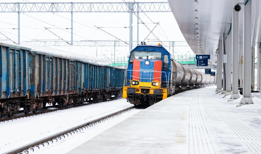 a colorful train traveling down train tracks near a station