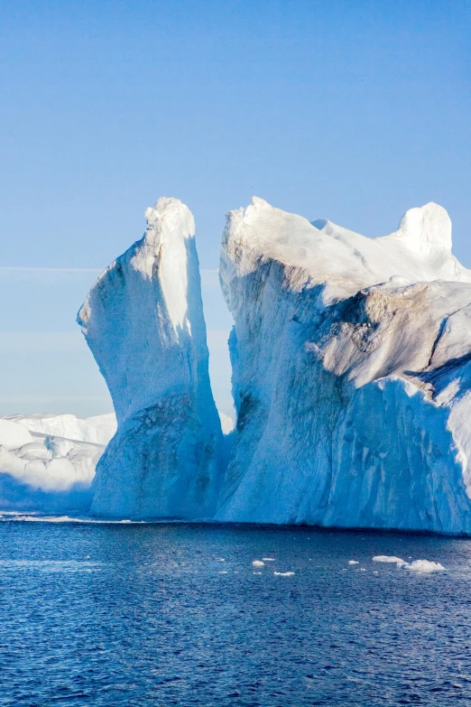 iceberg in ocean with blue sky and sun