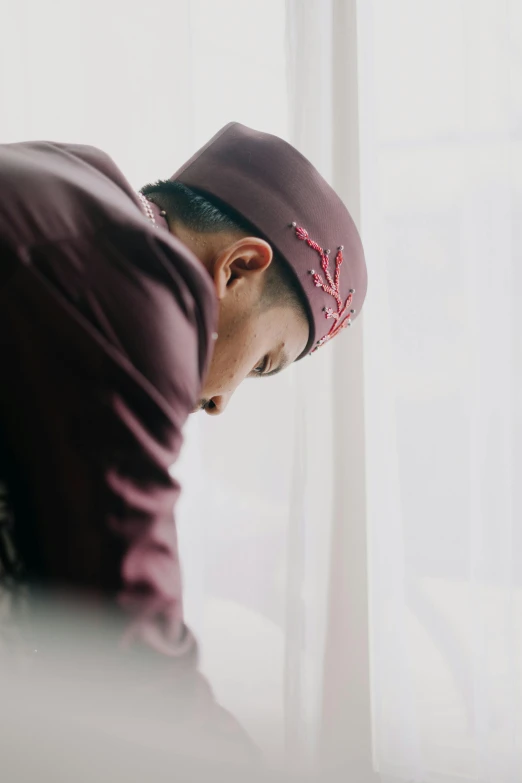 a man with a cap in front of a window