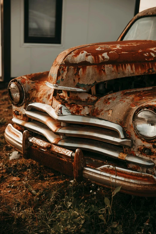 an old rusty car sits in the grass