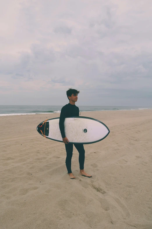 a man holding a surfboard on a sandy beach