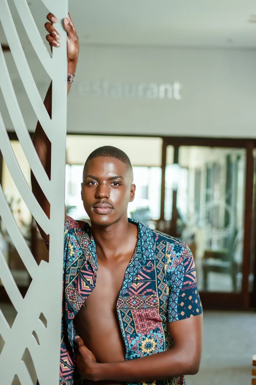 a man wearing a blue shirt is leaning against a pillar