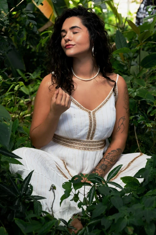a woman sits in a forest and looks off into the distance