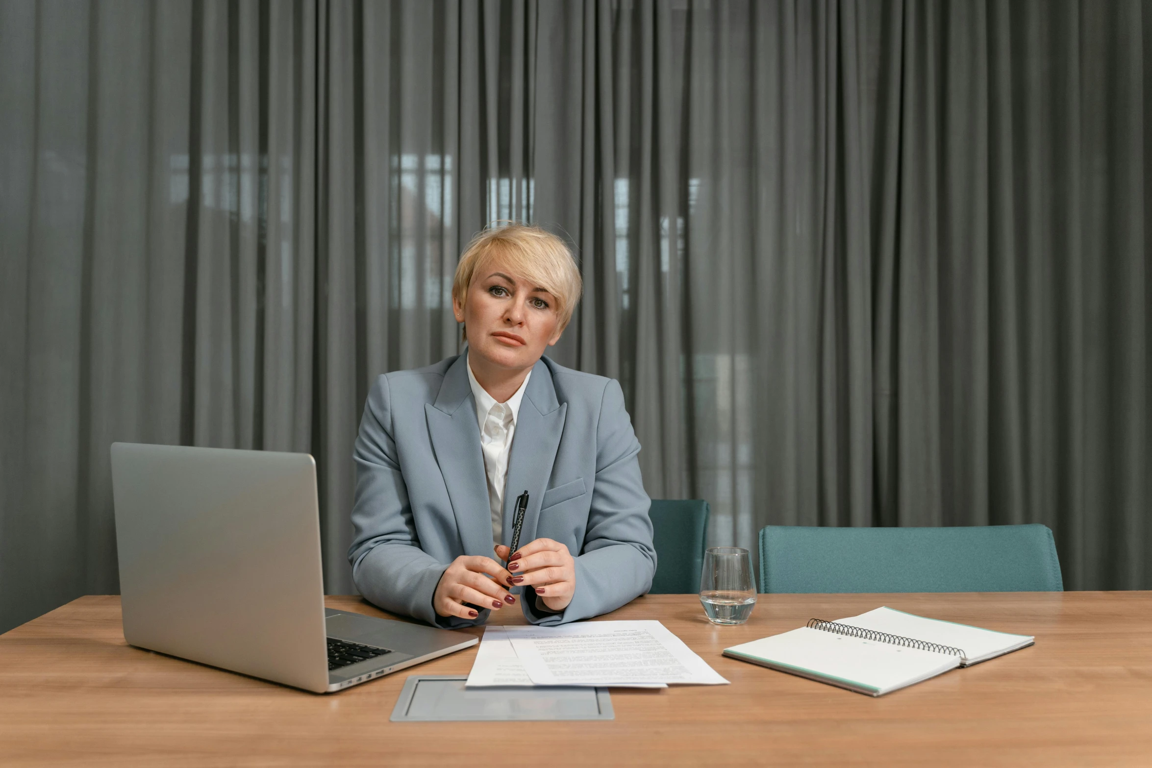 a lady sits at her desk and holds her hands over the keyboard and laptop