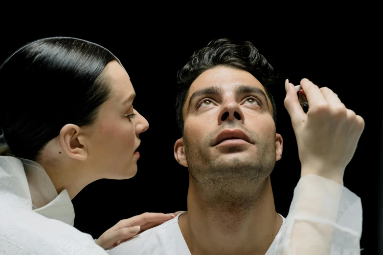 a woman is putting lipstick on a man's face