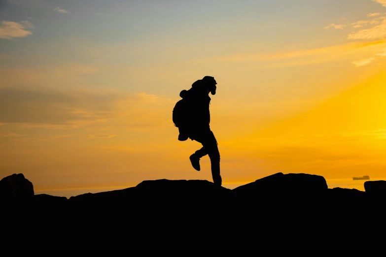 the silhouette of a woman jumping off a hill