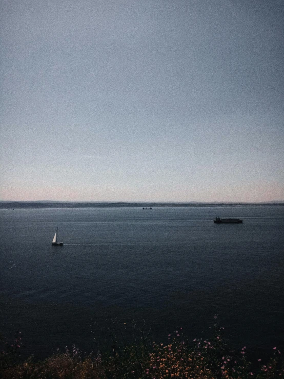 a small sailboat floats in the ocean on a bright day