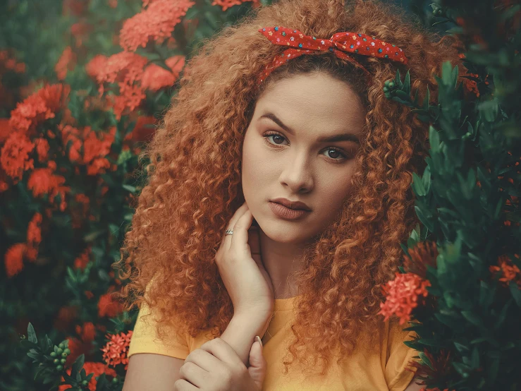 a girl in yellow shirt with red hair surrounded by flowers