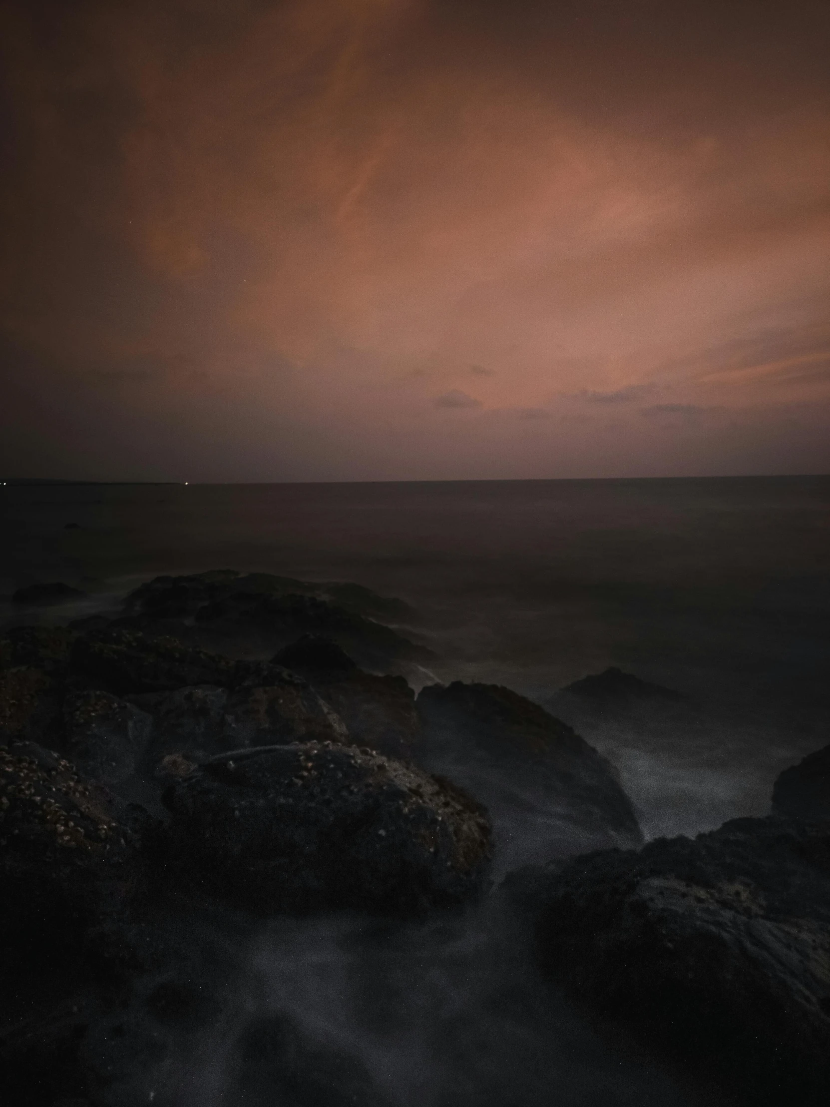 the view from a cliff at night looking towards the ocean