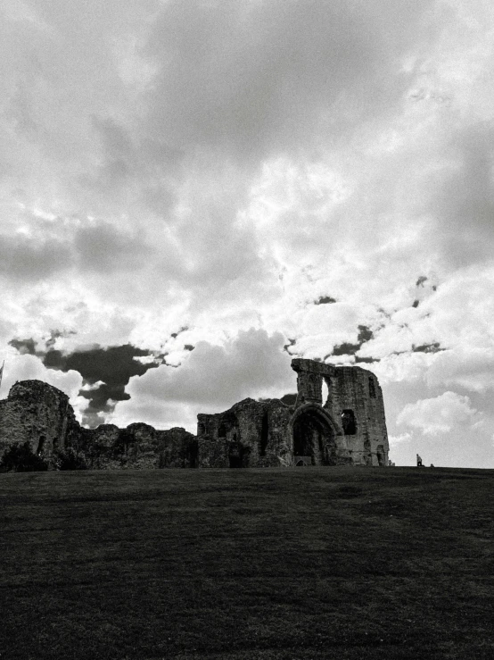 an old ruined structure stands on a grassy plain