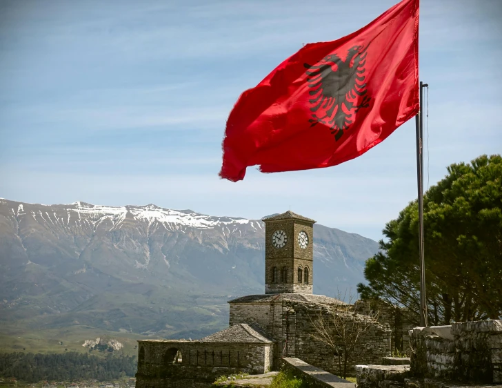 a flag is blowing in the wind in front of mountains