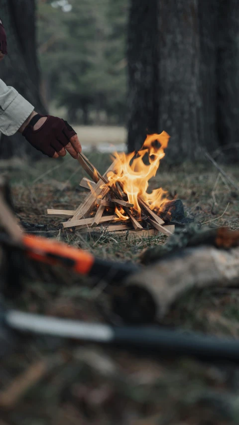 a person is cooking a campfire with a cooking tongs