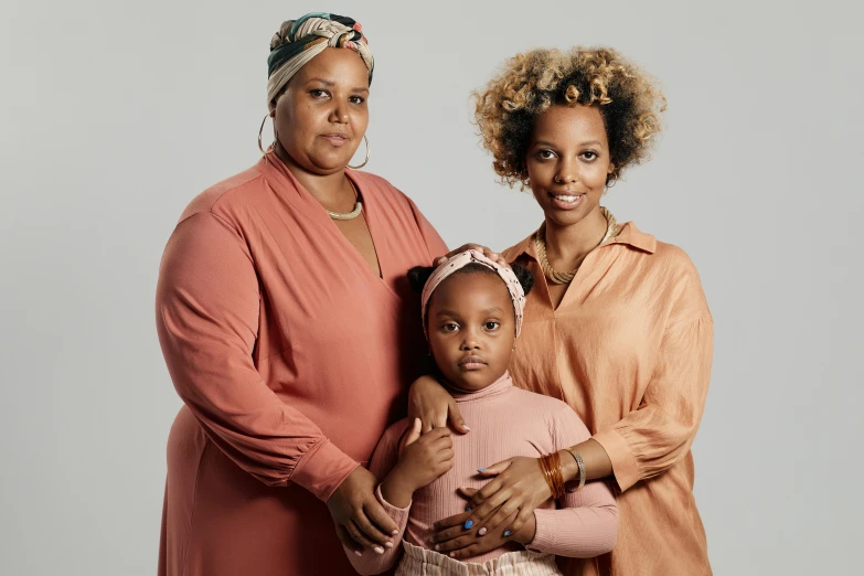 a woman and two girls are standing in front of a grey background