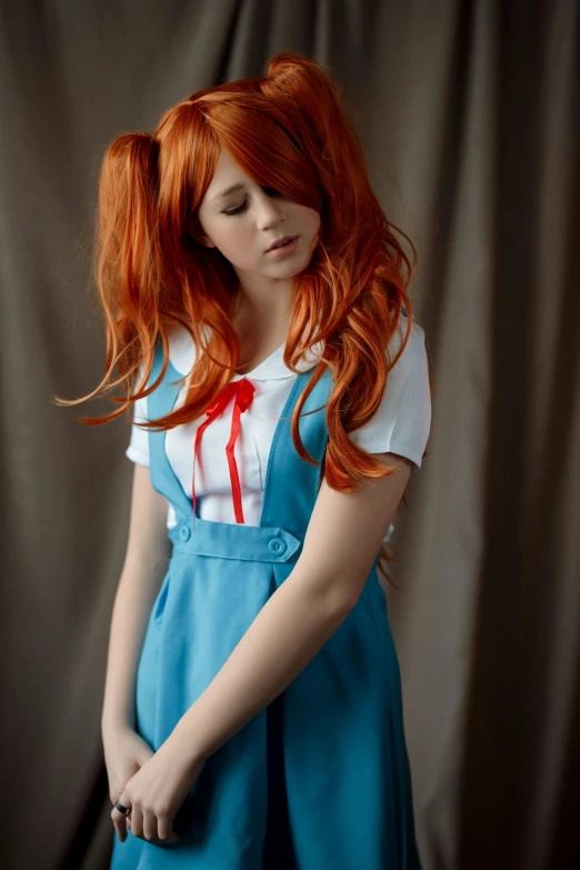 a red haired woman wearing a white shirt and blue skirt standing in front of a curtain