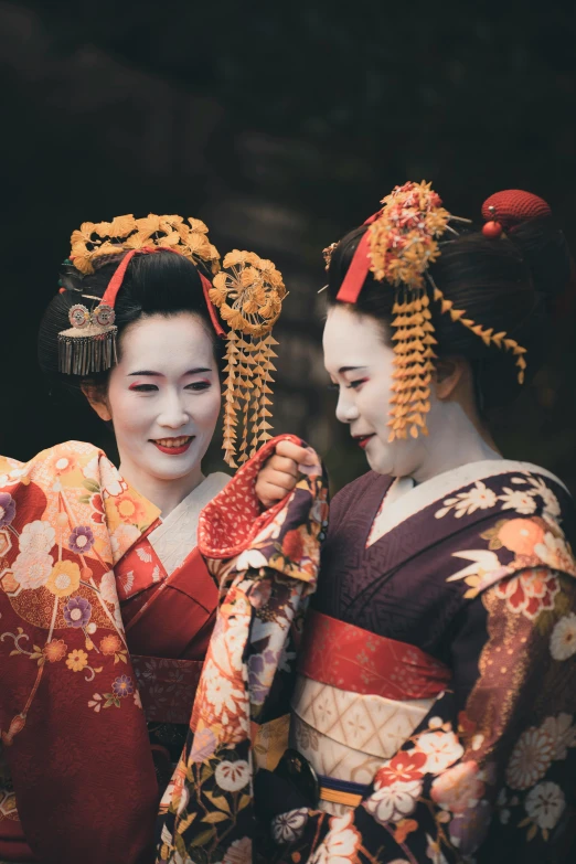 two asian women in traditional costume holding their hands together
