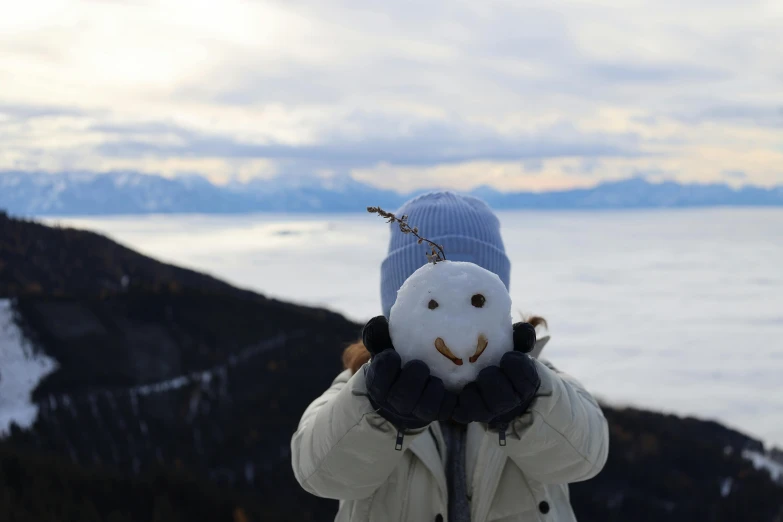 the snowman is covering his face with his mittens