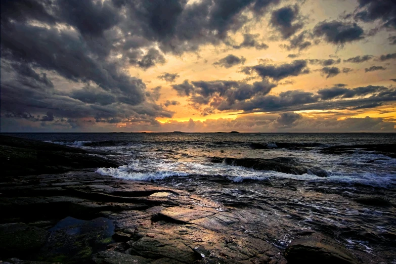 a body of water surrounded by rocks under a cloudy sky