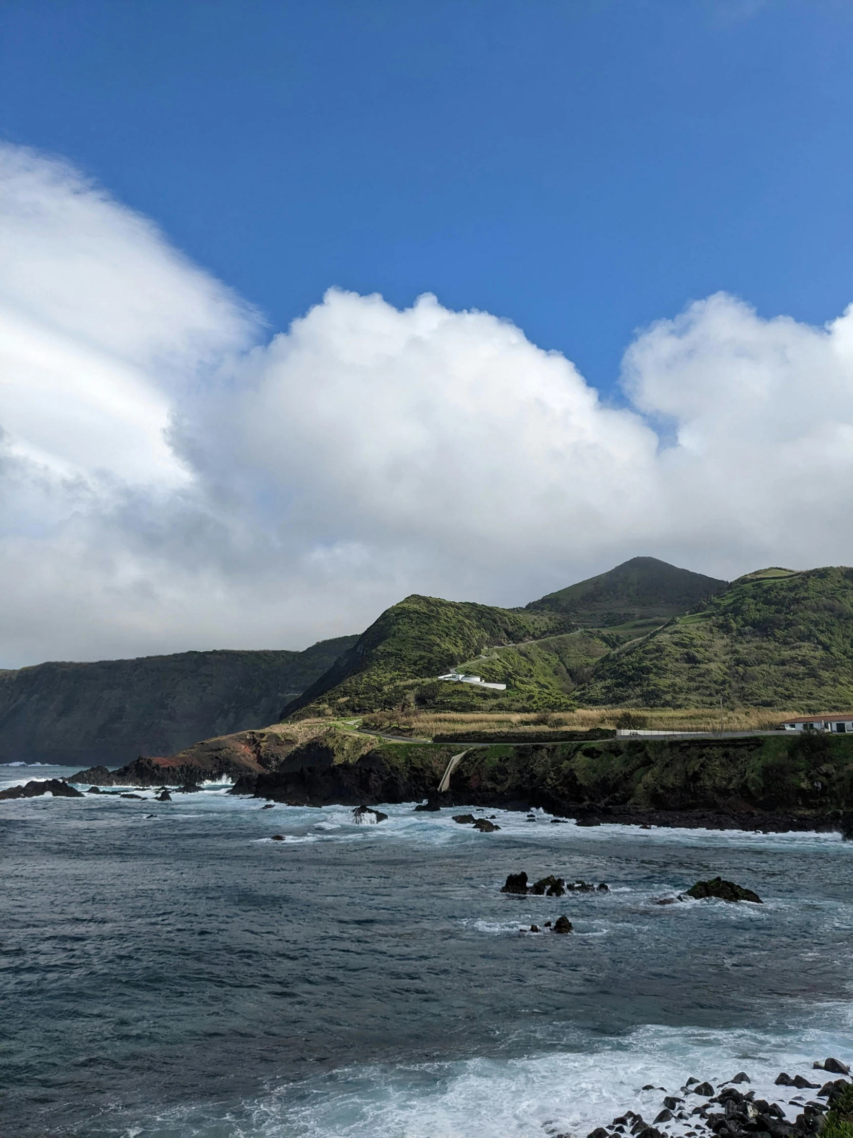 the coast line on a cloudy day has some green hills