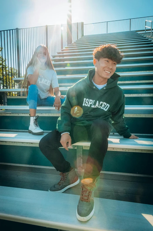 a boy wearing a sweatshirt and jogging shoes sits on some steps