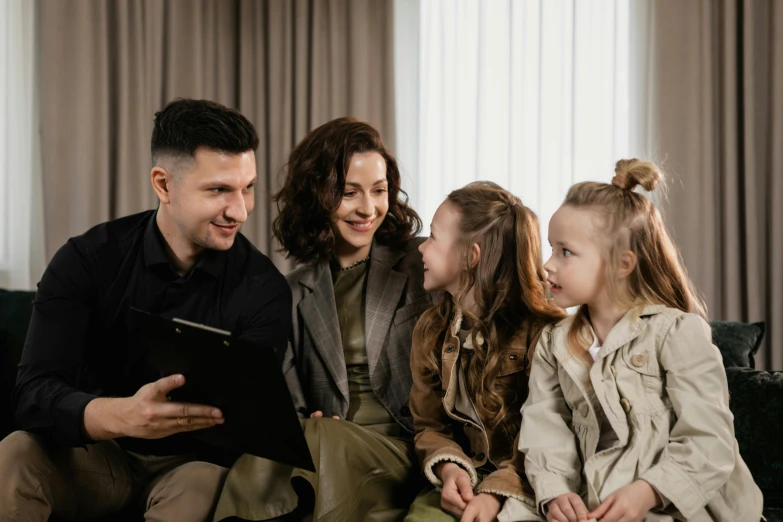 a man sitting next to two little girls on top of a couch