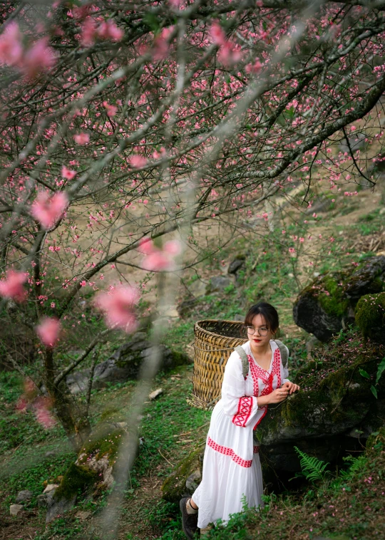 the woman is standing under pink blossoms in a park