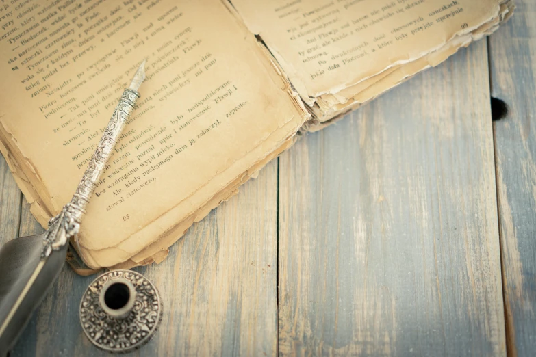 old book opened with an empty page with a feather quill resting next to it