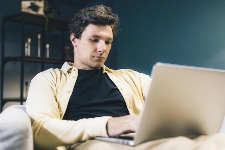 a man sitting on a couch working on his laptop